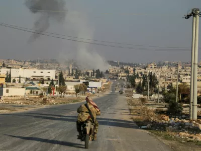 Smoke rises as a member of the rebels led by the Islamist militant group Hayat Tahrir al-Sham drives on a motorbike in al-Rashideen, Aleppo province, Syria November 29, 2024. REUTERS/Mahmoud Hasano