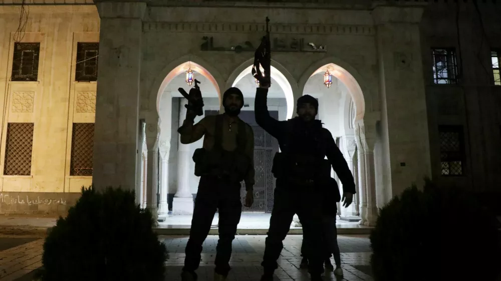 Rebel fighters hold weapons in front of Hama governor's building as they gather after Syrian rebels captured the city during their advance across northern Syria, in Hama, Syria December 5, 2024. REUTERS/Mahmoud Hassano