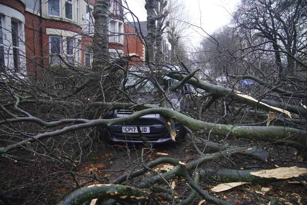 A car is seen underneath a fallen tree in Liverpool, England, during storm Darragh, Saturday, Dec. 7, 2024. (Peter Byrne/PA via AP)