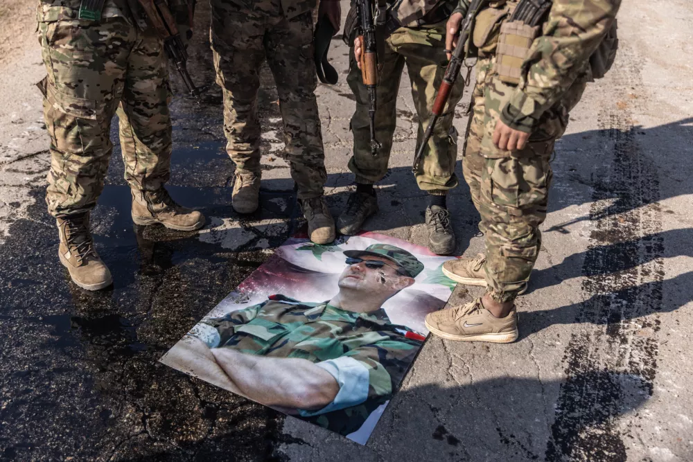 FILED - 29 November 2024, Syria, Kafr Naya: Syrian armed opposition fighters place their feet on a picture of Syrian President Bashar al-Assad after taking control of the town of Kafr Naya in the Aleppo countryside. The Syrian state army says the rule of al-Assad has come to an end, with the army command informing government soldiers they are no longer in service, dpa has learned from Syrian military circles. Photo: Anas Alkharboutli/dpa