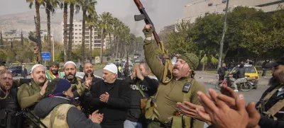 Opposition fighters celebrate the take over of the city by the insurgents in Damascus, Syria, Sunday Dec. 8, 2024. (AP Photo/Hussein Malla)