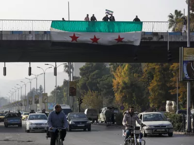 Syrians display and wave the Syrian opposition flag as they celebrate in Damascus, Syria, Monday, Dec. 9, 2024. (AP Photo/Omar Sanadiki)