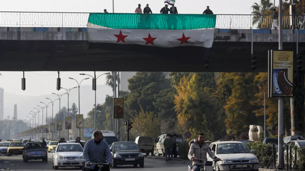 Syrians display and wave the Syrian opposition flag as they celebrate in Damascus, Syria, Monday, Dec. 9, 2024. (AP Photo/Omar Sanadiki)