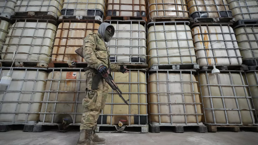 A Syrian member of the rebel group shows liquid material for manufacturing amphetamine pills known as Captagon hidden, at the warehouse where the drug was manufactured before the fall of Bashar Assad government at a facility in Douma city, outskirts of Damascus, Syria, Friday, Dec. 13, 2024. (AP Photo/Hussein Malla)