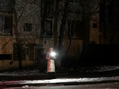 A woman holds a torch as she stands in a dark street during partial power cuts following a Russian attack on Ukrainian energy facilities, amid Russia's attack on Ukraine, in central Kyiv, Ukraine, December 13, 2024. REUTERS/Thomas Peter