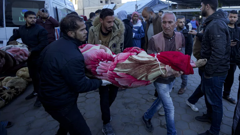 Palestinians carry the body of a relative killed in the Israeli bombardment of the Gaza Strip at a hospital in Deir al-Balah, Sunday, Dec. 15, 2024. (AP Photo/Abdel Kareem Hana)