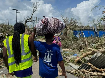 A man carries his belongings as rescue workers attempt to clear a blocked road, in the aftermath of Cyclone Chido, within Labattoir, in Mayotte, France, December 15, 2024. REUTERS/Chafion Madi