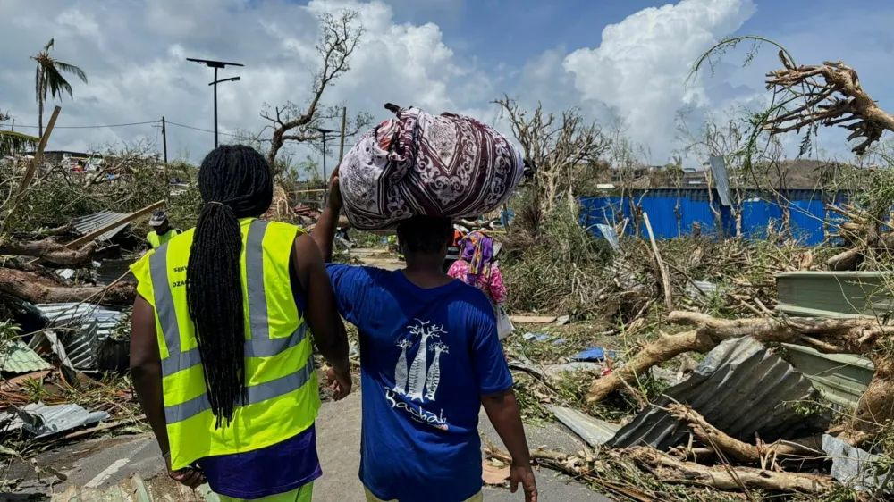 A man carries his belongings as rescue workers attempt to clear a blocked road, in the aftermath of Cyclone Chido, within Labattoir, in Mayotte, France, December 15, 2024. REUTERS/Chafion Madi