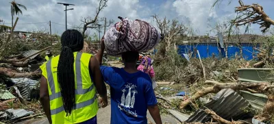 A man carries his belongings as rescue workers attempt to clear a blocked road, in the aftermath of Cyclone Chido, within Labattoir, in Mayotte, France, December 15, 2024. REUTERS/Chafion Madi