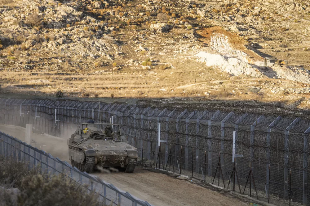 An Israeli armoured vehicle maneuvers along the security fence near the so-called Alpha Line that separates the Israeli-controlled Golan Heights from Syria, in the town of Majdal Shams, Sunday, Dec. 15, 2024. (AP Photo/Matias Delacroix)