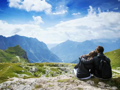 Couple of travelers (hikers) on top of a mountain enjoying valley view. Mangart is a mountain in the Julian Alps, located between Italy and Slovenia. Travel, Holidays, Freedom and Lifestyle Concept / Foto: Nataliaderiabina