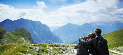 Couple of travelers (hikers) on top of a mountain enjoying valley view. Mangart is a mountain in the Julian Alps, located between Italy and Slovenia. Travel, Holidays, Freedom and Lifestyle Concept / Foto: Nataliaderiabina