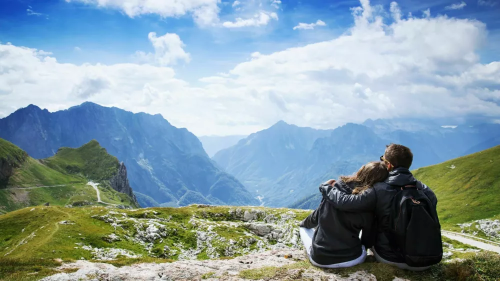 Couple of travelers (hikers) on top of a mountain enjoying valley view. Mangart is a mountain in the Julian Alps, located between Italy and Slovenia. Travel, Holidays, Freedom and Lifestyle Concept / Foto: Nataliaderiabina