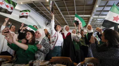 Syrian women wave "revolutionary" Syrian flags as they celebrate in a restaurant in Damascus, Syria, Tuesday, Dec. 17, 2024. (AP Photo/Omar Sanadiki)