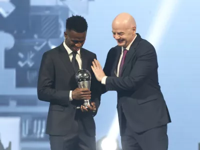 FIFA president Gianni Infantino, right, hugs Vinicius Junior of Real Madrid as he is awarded as the Best Men's FIFA Player during the FIFA Football Awards 2024 in Doha, Qatar, Tuesday, Dec. 17, 2024. (AP Photo/Hussein Sayed)