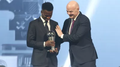 FIFA president Gianni Infantino, right, hugs Vinicius Junior of Real Madrid as he is awarded as the Best Men's FIFA Player during the FIFA Football Awards 2024 in Doha, Qatar, Tuesday, Dec. 17, 2024. (AP Photo/Hussein Sayed)