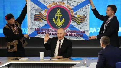 Men hold a replica of the banner of the 155th Marine Brigade of the Pacific Fleet, participating in a special military operation in Ukraine during Russian President Vladimir Putin's annual news conference and call-in show at Gostinny Dvor in Moscow, Russia, Thursday, Dec. 19, 2024. (AP Photo/Alexander Zemlianichenko)