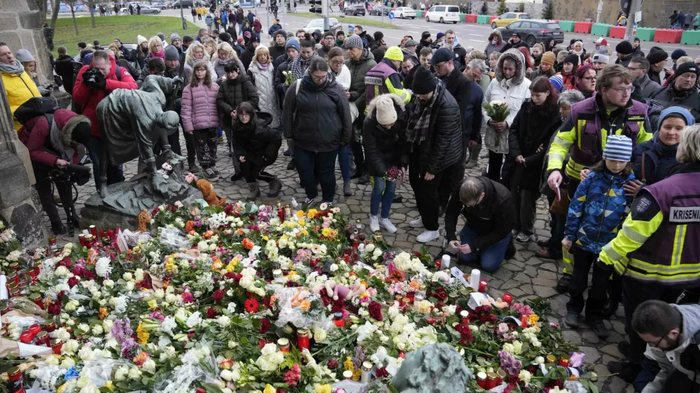 Citizens pay tribute for deaths outside St. John's Church near a Christmas Market, where a car drove into a crowd on Friday evening, in Magdeburg, Germany, Saturday, Dec. 21, 2024. (AP Photo/Ebrahim Noorozi)