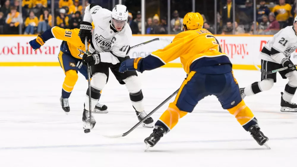 Dec 21, 2024; Nashville, Tennessee, USA; Los Angeles Kings center Anze Kopitar (11) skates with the puck as Nashville Predators defenseman Jeremy Lauzon (3) defends during the second period at Bridgestone Arena. Mandatory Credit: Steve Roberts-Imagn Images