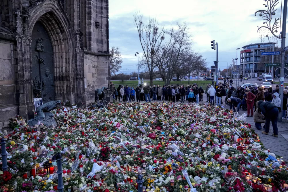 People lay flowers and lit candles in front of the Johannis church close to the Christmas market, where a car drove into a crowd on Friday evening, in Magdeburg, Germany, Sunday, Dec. 22, 2024. (AP Photo/Ebrahim Noroozi)