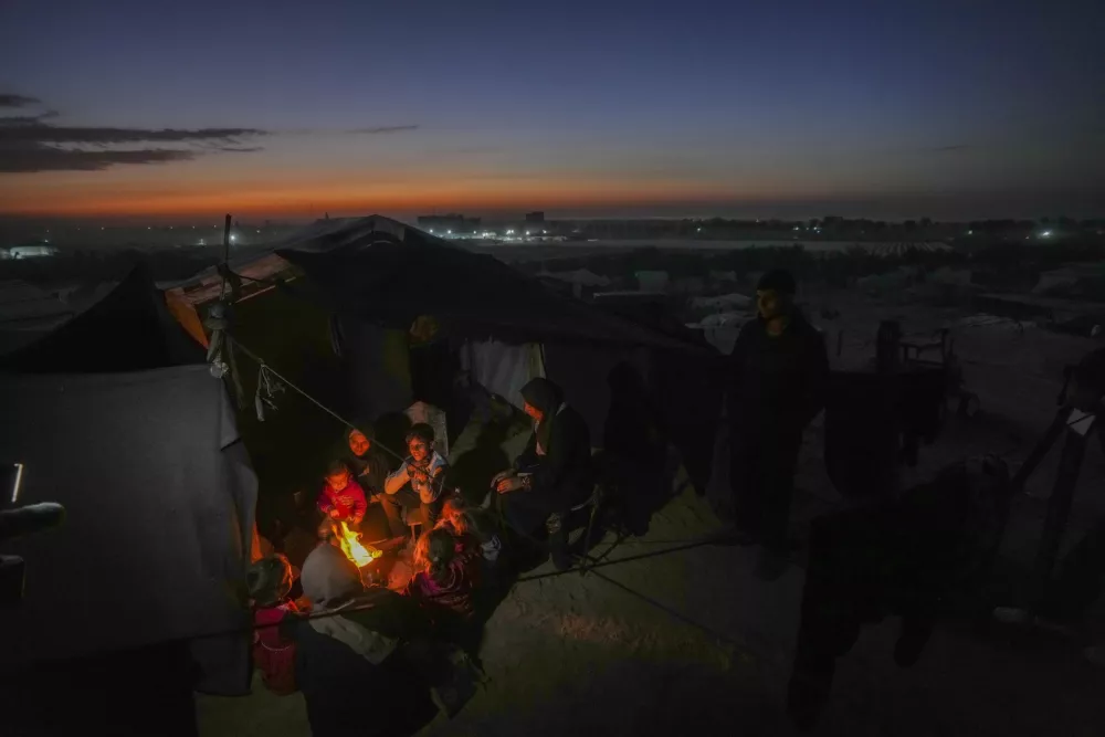 Reda Abu Zarada, 50, displaced from Jabaliya in nothern Gaza, sits by a fire with her grandchildren at a camp by the sea in Khan Younis, Gaza Strip, Thursday, Dec. 19, 2024. (AP Photo/Abdel Kareem Hana)