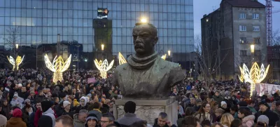 People gather around the bust of Dimitrije Tucovic, early 20th century Serbian socialist politician, during a protest against populist President Aleksandar Vucic and his government, in central Belgrade, Serbia, Sunday, Dec. 22, 2024. (AP Photo/Marko Drobnjakovic)