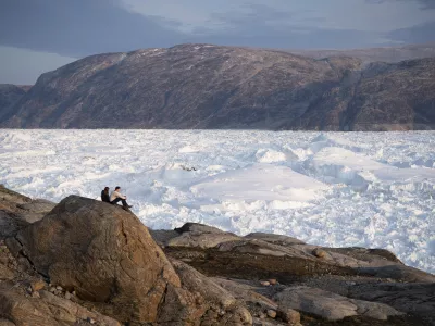 FILE - In this Aug. 16, 2019, file photo, NYU student researchers sit on top of a rock overlooking the Helheim glacier in Greenland. (AP Photo/Felipe Dana, File)