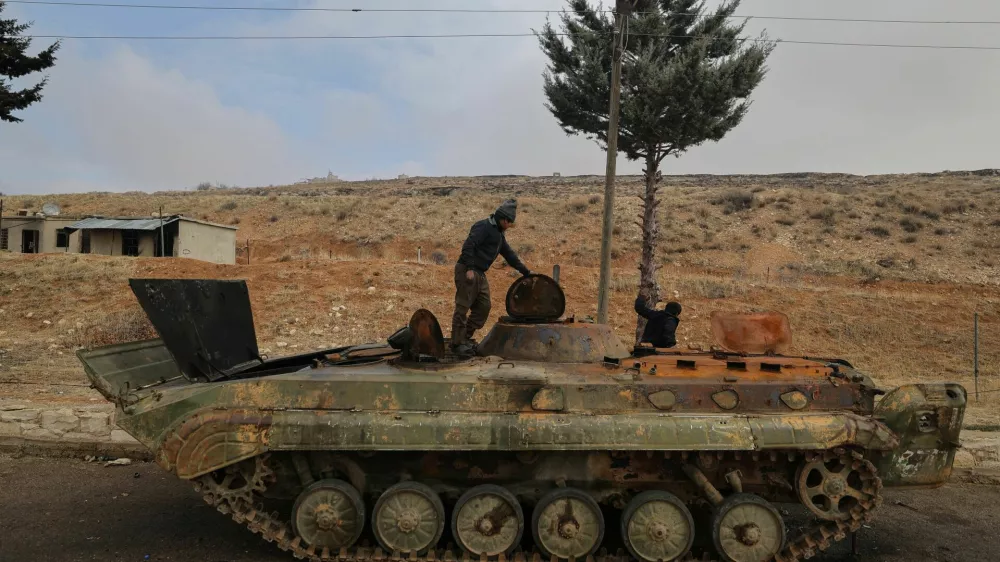 Ahmed and Khaled collect metal to sell from an abandoned Syrian army armoured personnel carrier (APC) outside Sednaya prison, which was known as a slaughterhouse under the rule of Syria's Bashar al-Assad, who was ousted, in Sednaya, Syria December 24, 2024. REUTERS/Zohra Bensemra