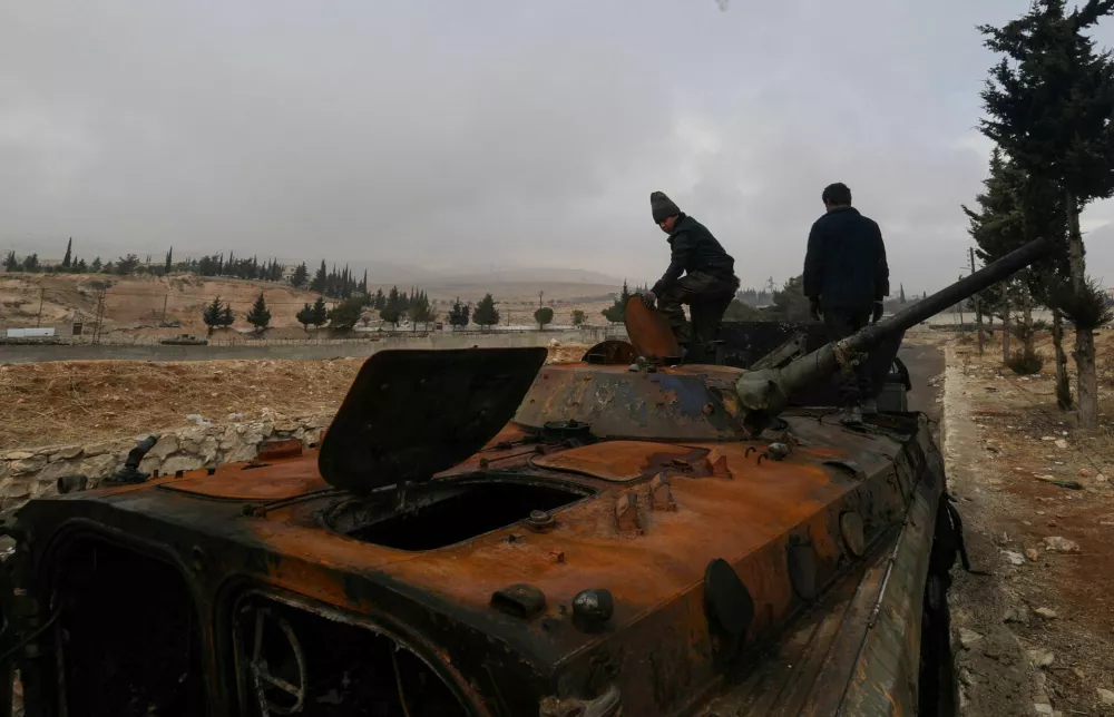 Ahmed and Khaled collect metal to sell from an abandoned Syrian army armoured personnel carrier (APC) outside Sednaya prison, which was known as a slaughterhouse under the rule of Syria's Bashar al-Assad, who was ousted, in Sednaya, Syria December 24, 2024. REUTERS/Zohra Bensemra