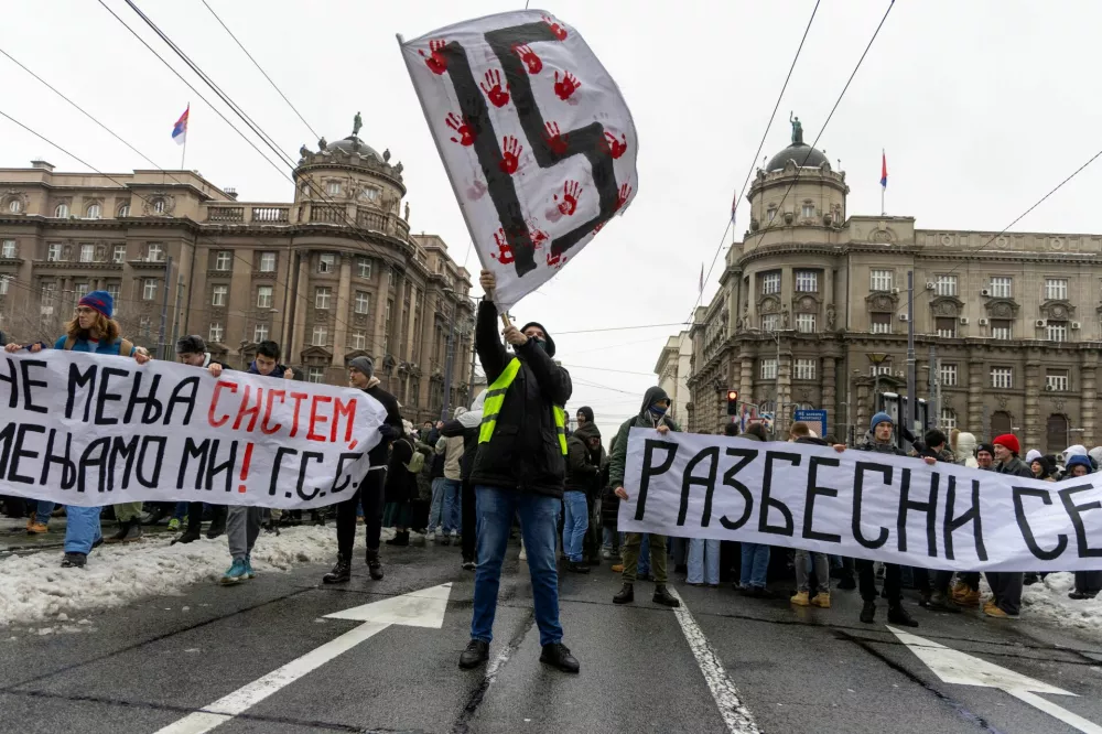 A student waves a flag, as others hold banners and chant slogans during a protest, demanding action from the state prosecutor in the case of the deaths of the victims in the Novi Sad railway station disaster in November, in Belgrade, Serbia, December 25, 2024. REUTERS/Djordje Kojadinovic