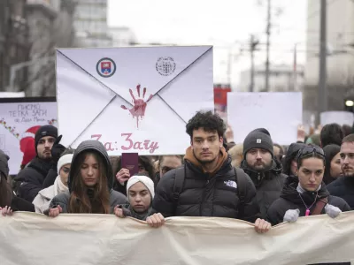 People stopping traffic, stand in silence during ongoing protests that erupted after a concrete canopy fell last month and killed 15 people in front of the government building in Belgrade, Serbia, Wednesday, Dec. 25, 2024. (AP Photo/Darko Vojinovic)