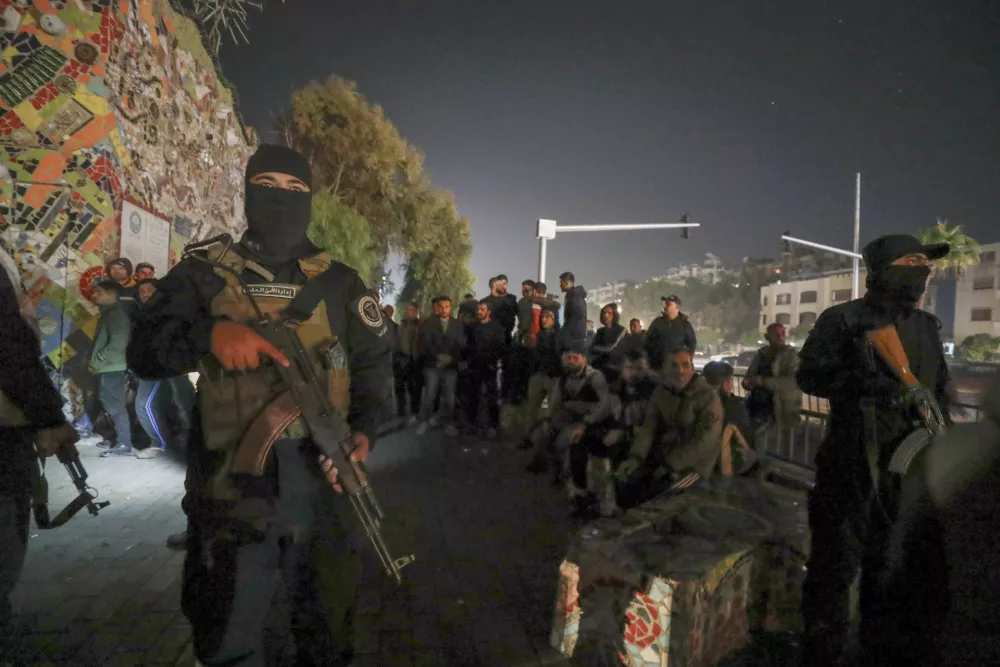 Security forces of the new Syrian government secure the area around group of Alawite protesters in the Mazzeh district in Damascus Wednesday Dec. 25, 2024. The minority Alawite community is an offshoot of Shiite Islam that form President Bashar Assad belongs to. (AP Photo/Omar Sanadiki)