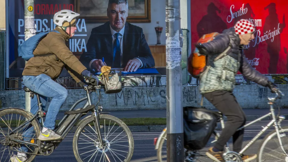 Cyclists ride past a poster of incumbent President Zoran Milanovic ahead of the presidential election in Zagreb, Croatia, Thursday, Dec. 26, 2024. (AP Photo)