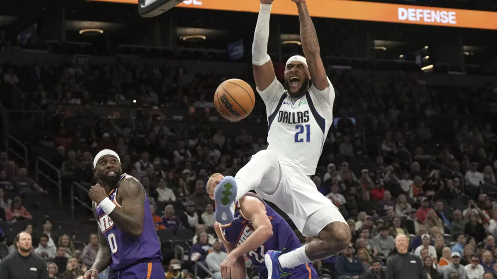 Dallas Mavericks center Daniel Gafford dunks over Phoenix Suns forward Ryan Dunn (0) and center Mason Plumlee during the second half of an NBA basketball game, Friday, Dec. 27, 2024, in Phoenix. Dallas won 98-89. (AP Photo/Rick Scuteri)