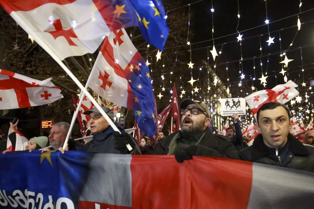 Demonstrators with Georgian national and EU flags march during an anti-government rally outside the Parliament building in Tbilisi, Georgia, on Saturday, Dec. 28, 2024. (AP Photo/Zurab Tsertsvadze)