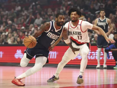 Dallas Mavericks guard Kyrie Irving (11) drives to the basket as Portland Trail Blazers guard Shaedon Sharpe (17) defends during the first half of an NBA basketball game Saturday, Dec. 28, 2024, in Portland, Ore. (AP Photo/Amanda Loman)