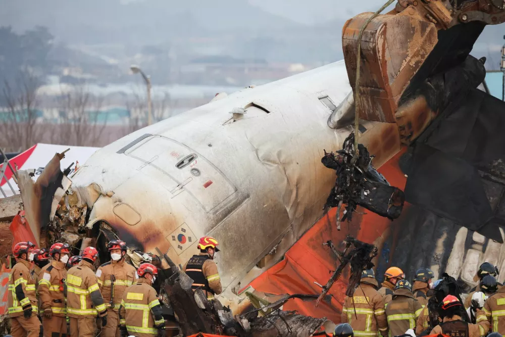 An excavator is used to lift burnt chairs from the wreckage of an aircraft that crashed after it went off the runway at Muan International Airport, in Muan, South Korea, December 29, 2024. REUTERS/Kim Hong-Ji