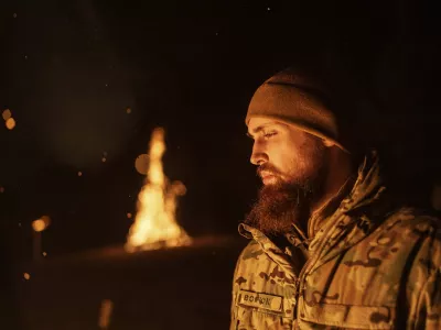 A Ukrainian serviceman aka Vovchok of 3rd assault brigade throws gunpowder into a fire during memorial ceremony of his fallen comrades during the winter solstice in Kharkiv region, Ukraine, Dec. 22, 2024. (AP Photo/Evgeniy Maloletka)