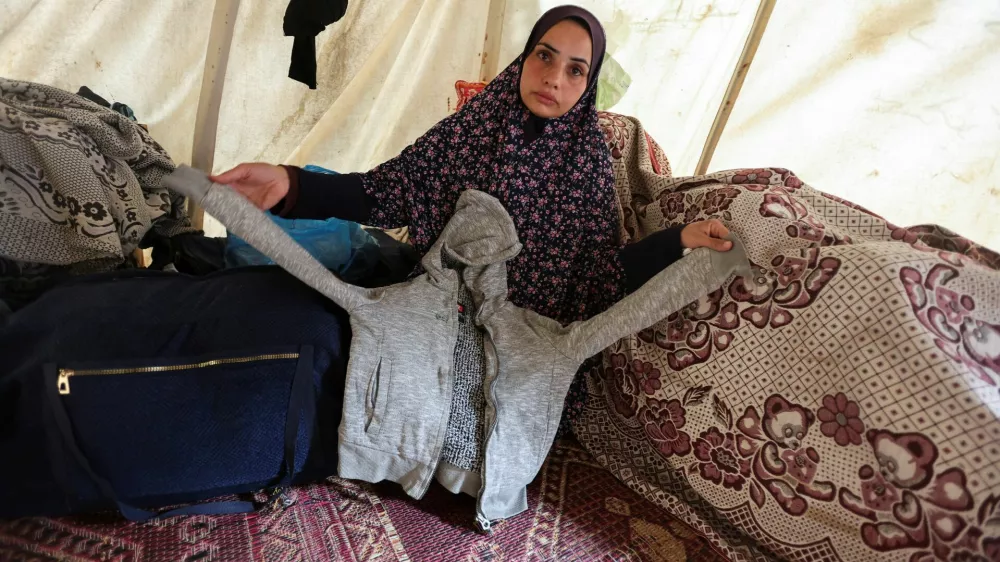 Asmaa, the mother of 9-year-old Palestinian boy Ramadan Hamed, who doctors said died due to malnutrition, shows her son's clothing inside a tent where she shelters after being displaced from her home, in Nusierat in the central Gaza Strip December 7, 2024. REUTERS/Ramadan Abed