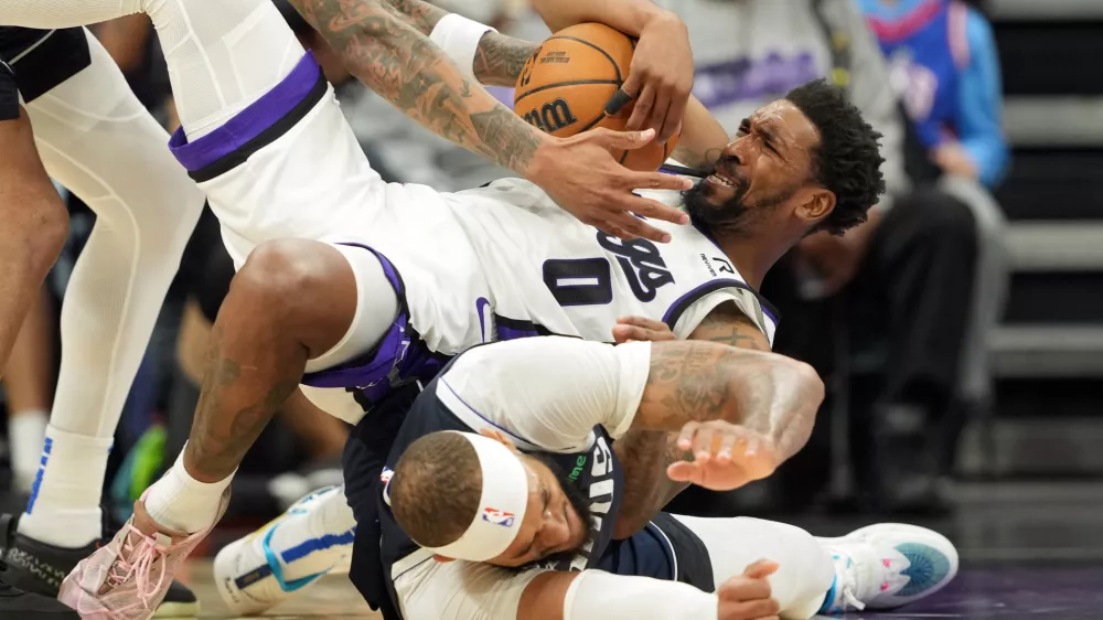 Dec 30, 2024; Sacramento, California, USA; Sacramento Kings guard Malik Monk (0) falls on top of Dallas Mavericks center Daniel Gafford (bottom) during the third quarter at Golden 1 Center. Mandatory Credit: Darren Yamashita-Imagn Images