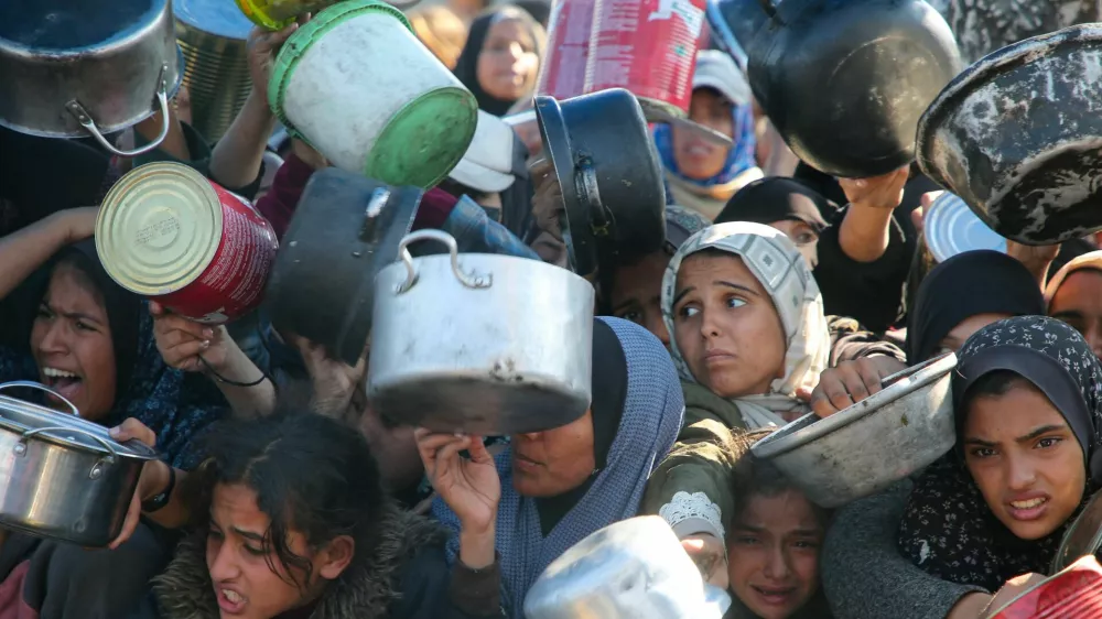 Palestinians gather to receive food cooked by a charity kitchen, amid a hunger crisis, as the Israel-Hamas conflict continues, in Khan Younis in the southern Gaza Strip, January 2, 2025. REUTERS/Hatem Khaled