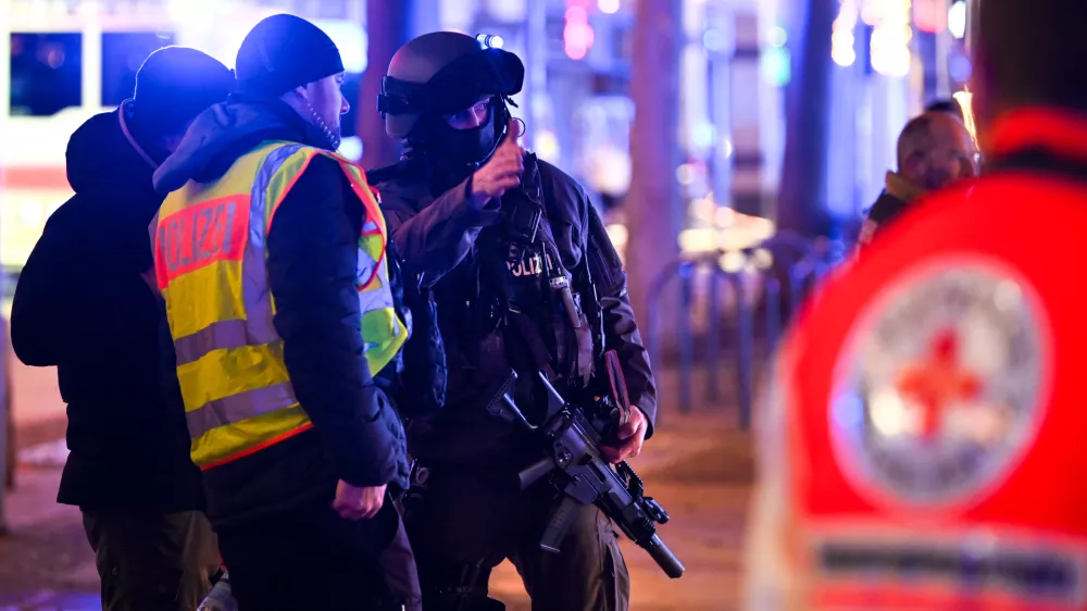 FILED - 20 December 2024, Saxony-Anhalt, Magdeburg: An armed police officer speaks with his colleagues at the the Magdeburg incident scene. The suspect in the deadly car-ramming incident at a Christmas market in the German city of Magdeburg had appeared in seven investigative proceedings in the two years prior to the attack, dpa has learned from security sources. Photo: Heiko Rebsch/dpa