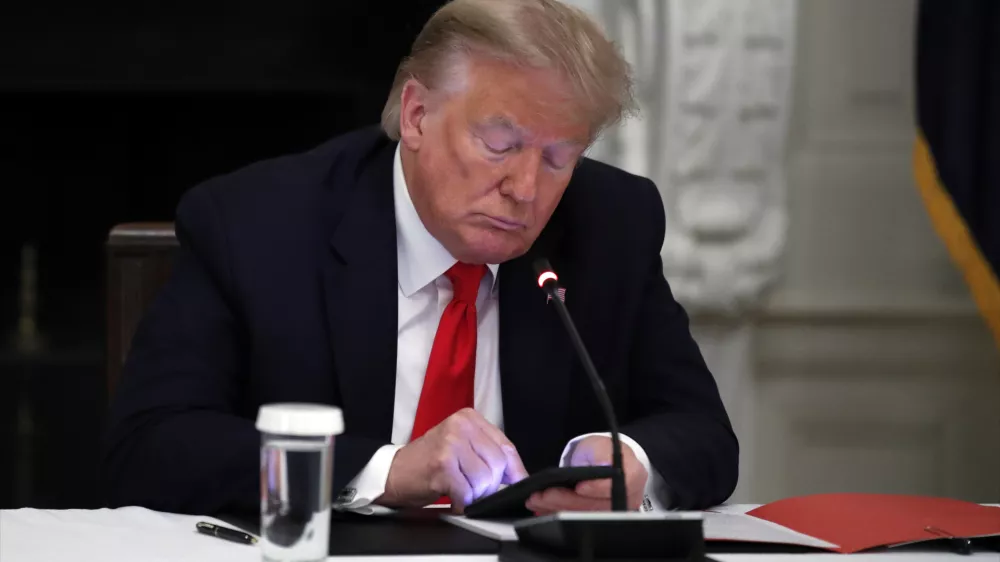 FILE - In this Thursday, June 18, 2020 file photo, President Donald Trump looks at his phone during a roundtable with governors on the reopening of America's small businesses, in the State Dining Room of the White House in Washington. On Wednesday, Jan. 25, 2023, Facebook parent Meta said in a blog post it is reinstating former President Trump's personal account after two-year suspension following the Jan. 6 insurrection. (AP Photo/Alex Brandon, File)