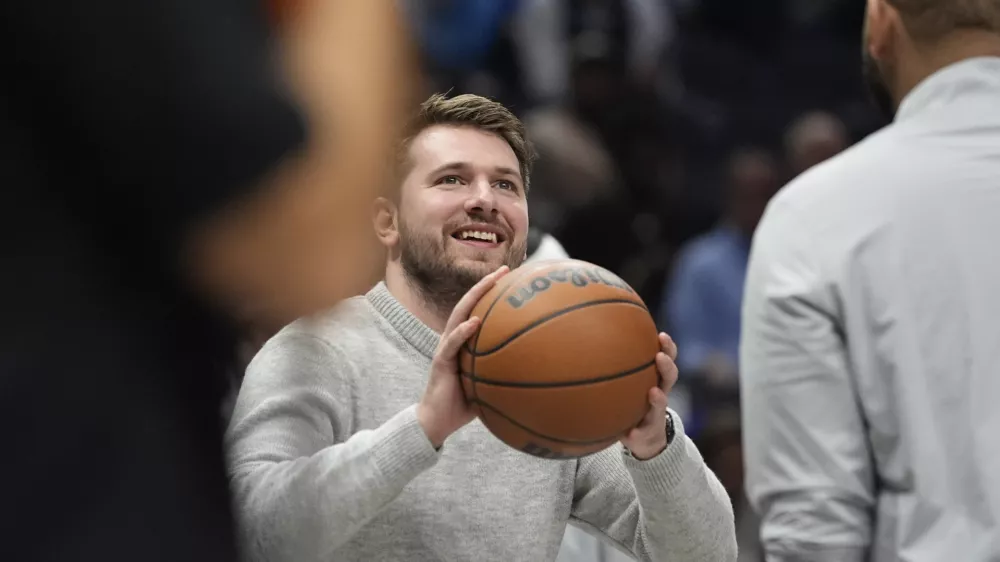 Injured Dallas Mavericks guard Luka Doncic plays with the game ball during a timeout in the first half of an NBA basketball game against the Los Angeles Lakers, Tuesday, Jan. 7, 2025, in Dallas. (AP Photo/LM Otero)