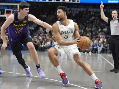 Dallas Mavericks guard Quentin Grimes (5) moves the ball against Los Angeles Lakers guard Austin Reaves (15) during the first half of an NBA basketball game Tuesday, Jan. 7, 2025, in Dallas. (AP Photo/LM Otero)