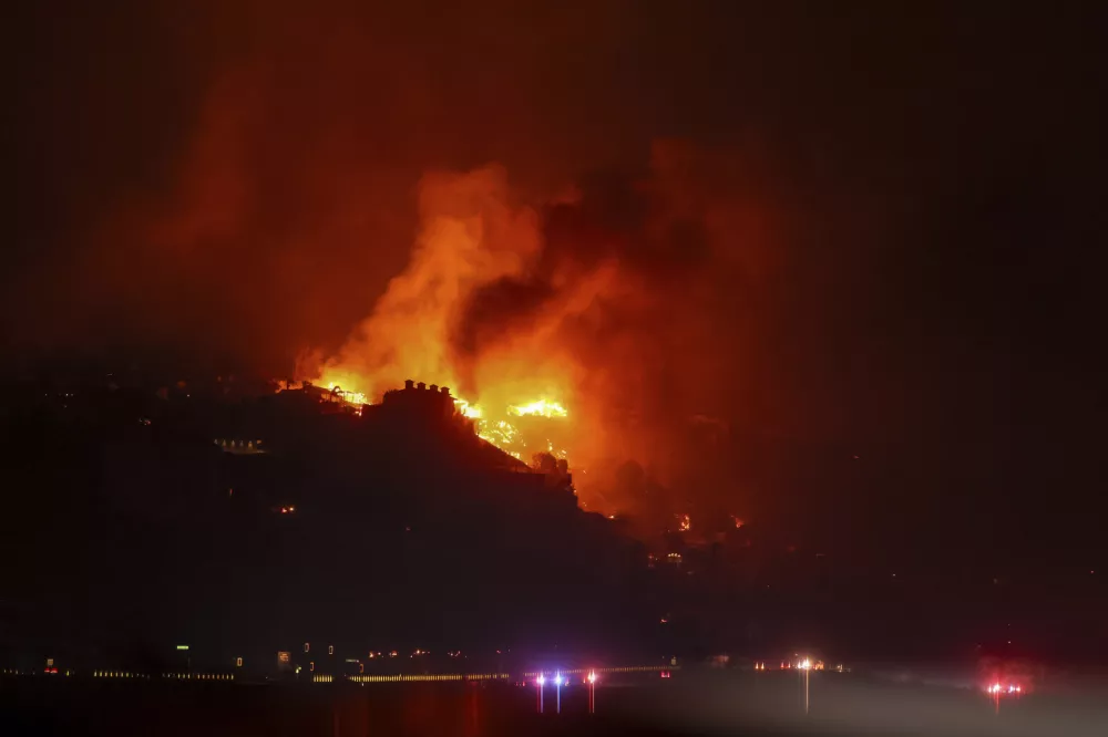 The Palisades Fire burns houses in the hill next to the Getty Villa Wednesday, Jan. 8, 2025 in Pacific Palisades, Calif. (AP Photo/Etienne Laurent)