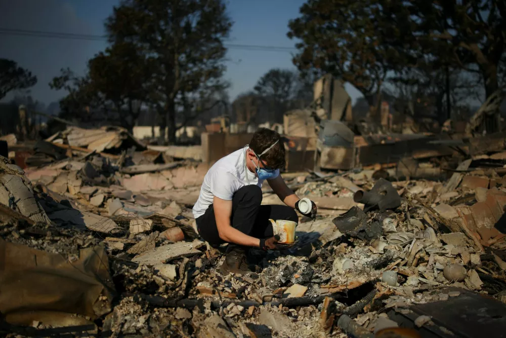 Resident Drew Cogan looks at his belonging at the remains of his burnt house, after powerful winds fueling devastating wildfires in the Los Angeles area forced people to evacuate, in the Pacific Palisades neighborhood on the west side of Los Angeles, California, U.S. January 9, 2025. REUTERS/Daniel Cole