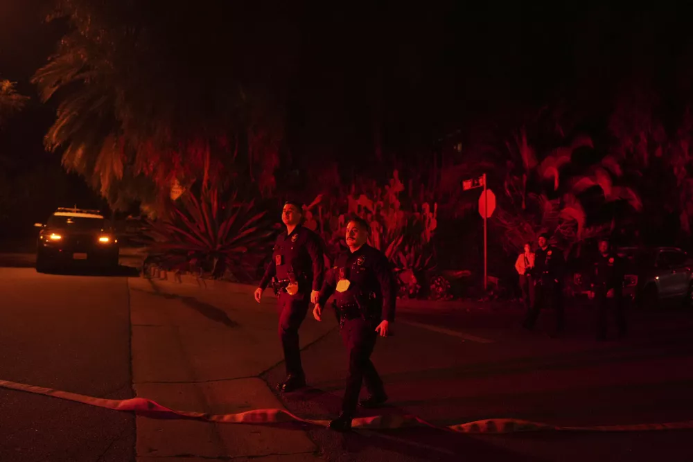 Police officers check on homes to evacuate residents near the Palisades Fire in Mandeville Canyon, Friday, Jan. 10, 2025, in Los Angeles. (AP Photo/Eric Thayer)