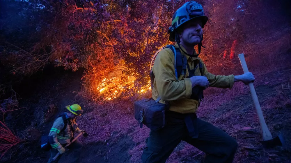 Firefighters extinguish a fire as the Palisades Fire, one of several simultaneous blazes that have ripped across Los Angeles County, burns in Mandeville Canyon, a neighborhood of Los Angeles, California, U.S., January 12, 2025. REUTERS/Ringo Chiu