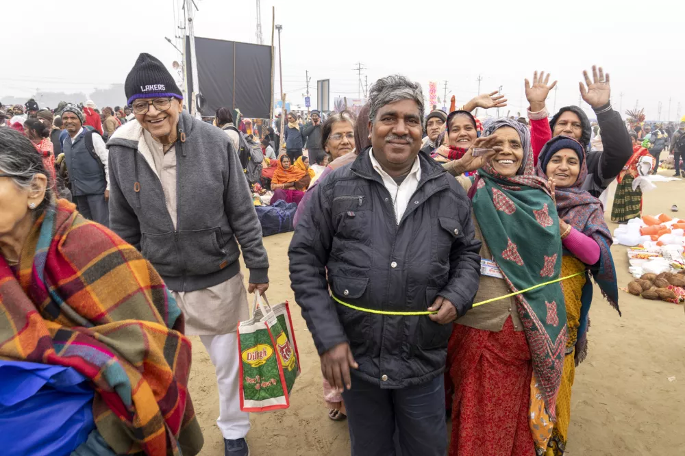 Hindu devotees use a rope to keep the members of a group together as they arrive to bathe at the confluence of the Ganges, the Yamuna and the mythical Saraswati rivers on the first day of the 45-day-long Maha Kumbh festival in Prayagraj, India, Monday, Jan. 13, 2025. (AP Photo/Ashwini Bhatia)